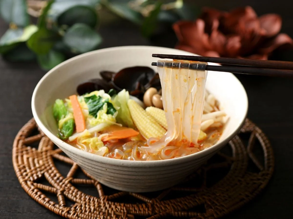 麻辣湯(マーラータン)の器と、箸で持ち上げられた春雨と野菜