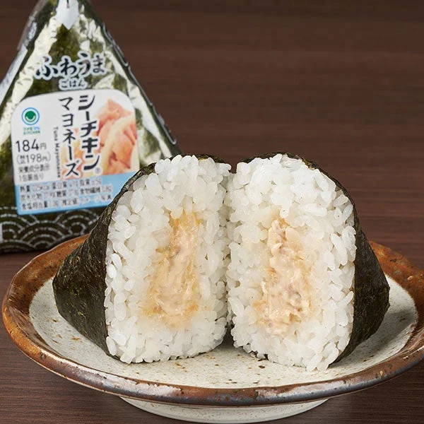 手巻 シーチキン®マヨネーズの包装と、海苔で巻かれたおむすびを半分に切った断面