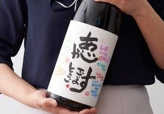 寄せ書きが書かれた芋焼酎ボトル