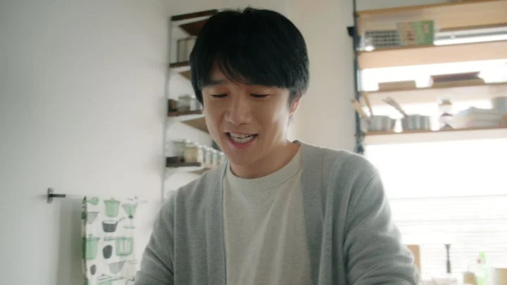 キッチンで灰色のカーディガンを着た男性が笑顔で話している