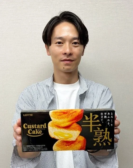 半熟カスタードケーキのパッケージを持つ久保田祐揮氏