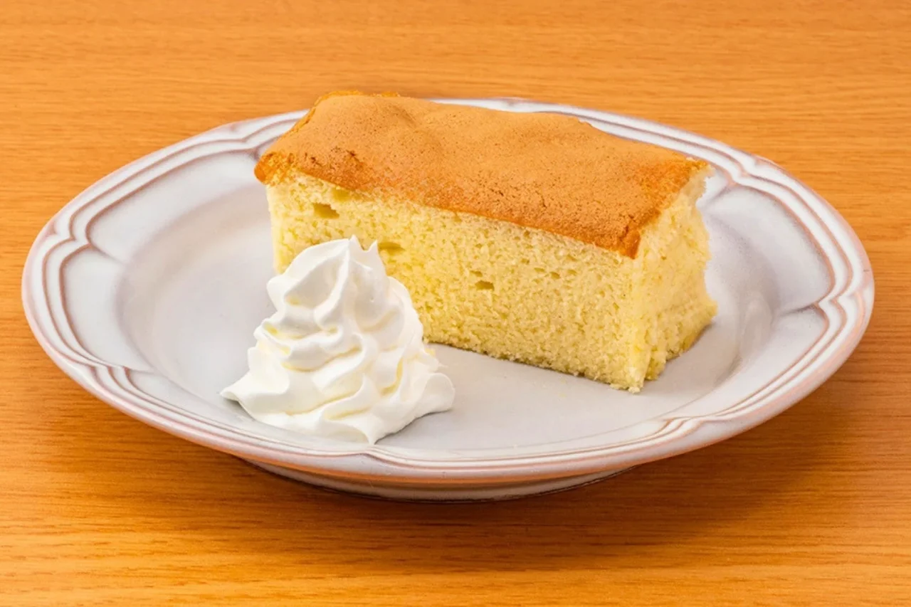 台湾カステラ。白い皿に角切りのスポンジケーキとホイップクリームを添えた外観。