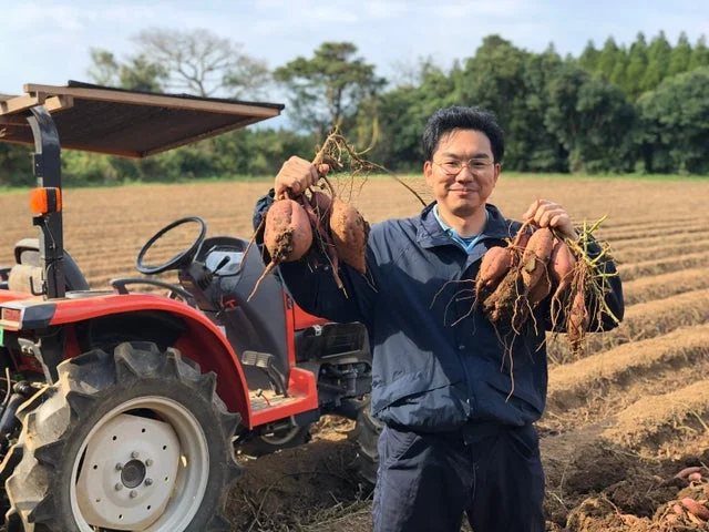 畑で収穫したての安納芋を持つ生産者の男性