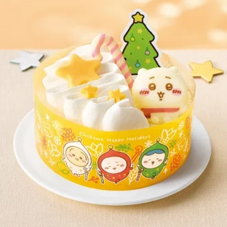 パペットスンスン クリスマスチョコケーキ。黄色い箱にキャラクターが描かれ、ホイップクリームと星型チョコ、ツリーピックで飾られたケーキ。