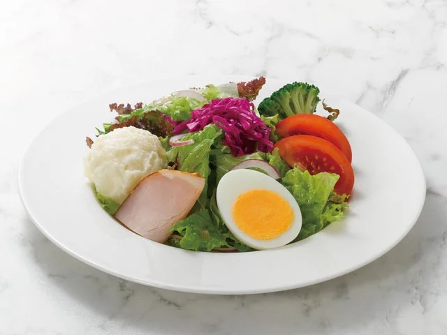 野菜、ロースハム、ゆで卵が盛られたサラダ