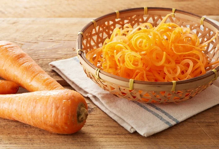 竹ざるに入った細切り甘にんじんと、横に置かれた生のにんじん