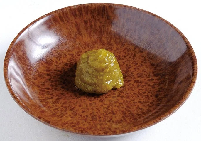 茶色の陶器の皿に盛られた黄緑色の柚子胡椒