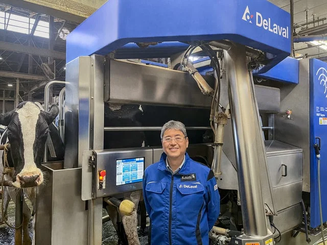 DeLavalのロボット搾乳装置の前に立つ男性と牛