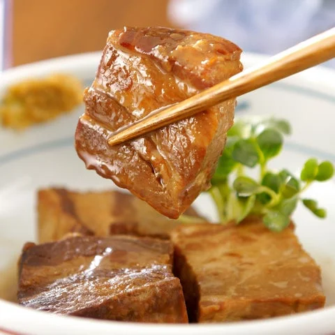 箸で持ち上げられたやわらかな豚角煮の調理例