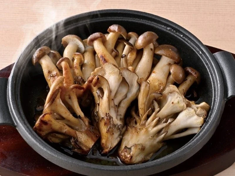 しめじと舞茸のステーキ。黒い器にきのこが盛り付けられている