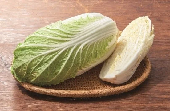 丸ごとと半分に切った白菜が編み込みの皿に置かれている