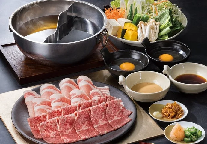 黒毛和牛と豚肉、野菜、鍋が並ぶセット