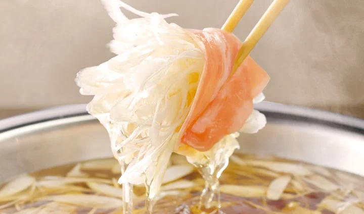 箸で持ち上げられた肉に巻いた薄切りねぎの巻きしゃぶ