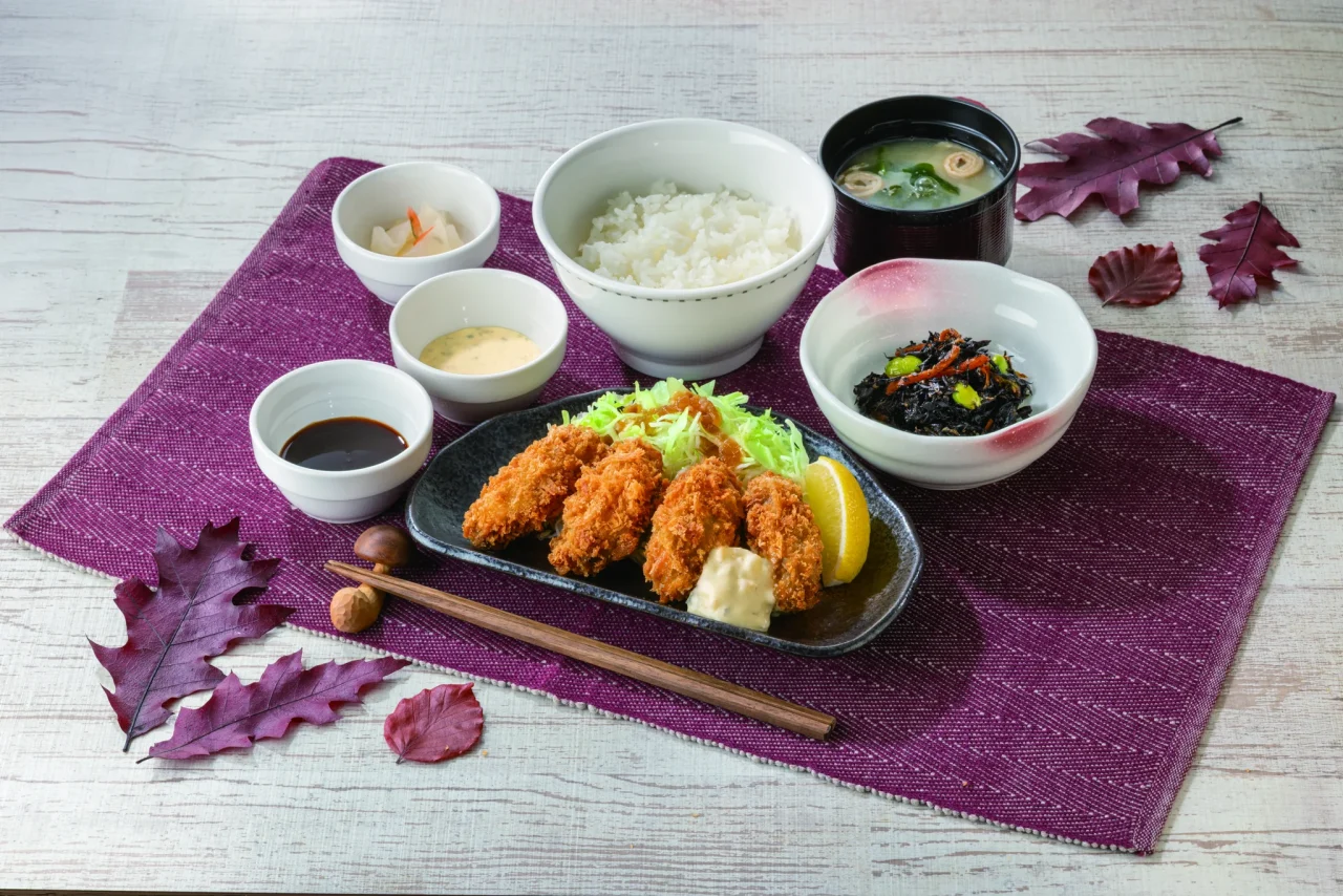 カキフライ和膳［４個］の和食膳。ご飯、味噌汁、漬物、タルタルソース、レモンを添えたカキフライが写る。