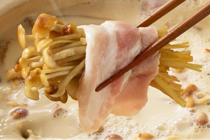 箸で味えのきと豚しゃぶを巻き、鍋から持ち上げる様子