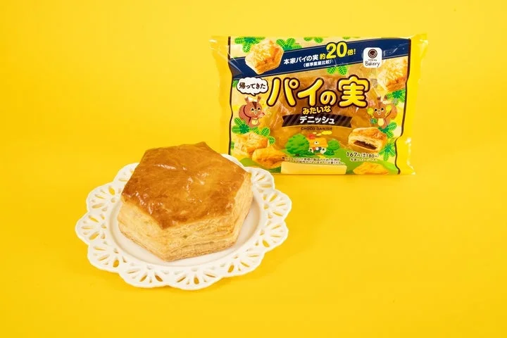 黄色い背景に、白い皿に乗った六角形のデニッシュと、そのパッケージが写っている