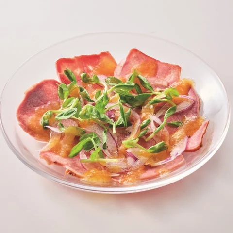 薄切り肉に野菜とソースを添えたサラダ料理