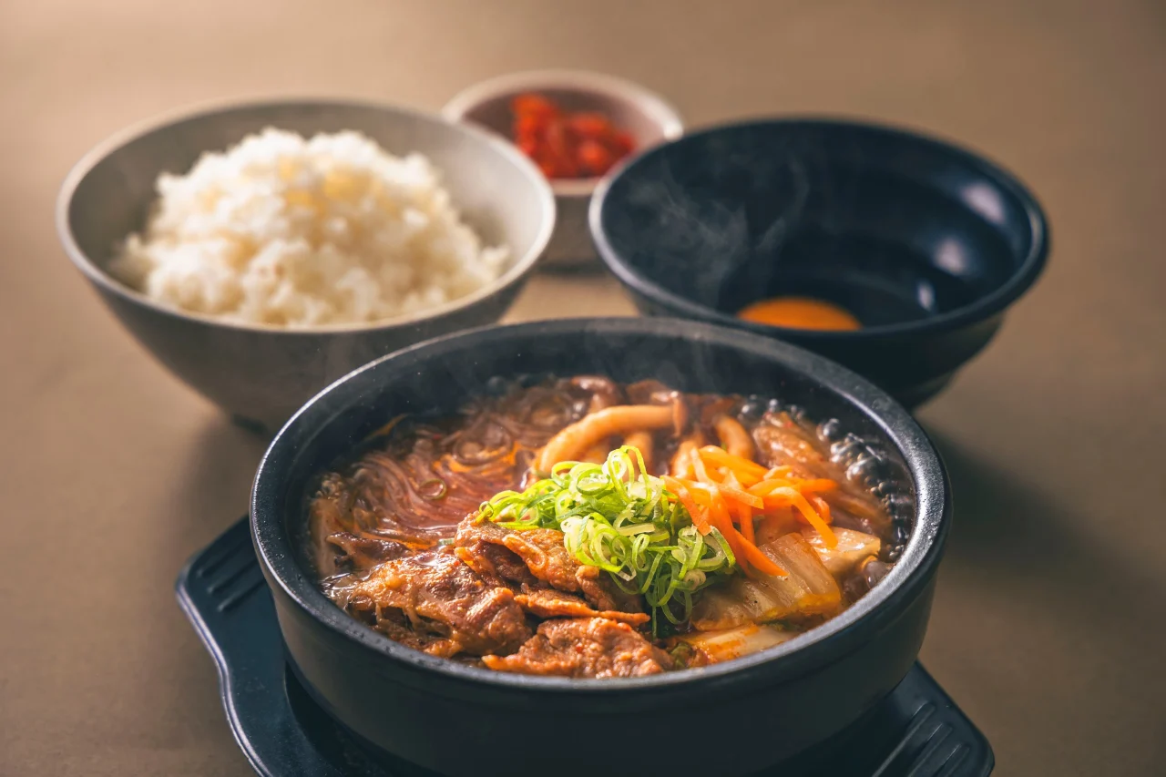 牛プルコギ定食。鉄板に牛肉と野菜、ご飯と卵黄を添えて提供