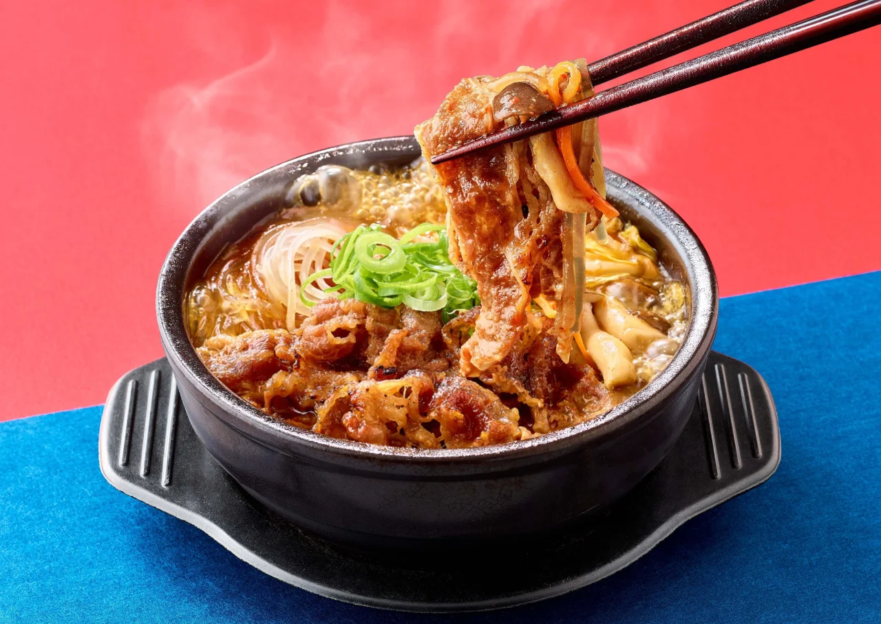 牛プルコギ定食の鉄板料理。箸で牛肉と野菜を掴み、湯気が立つ様子