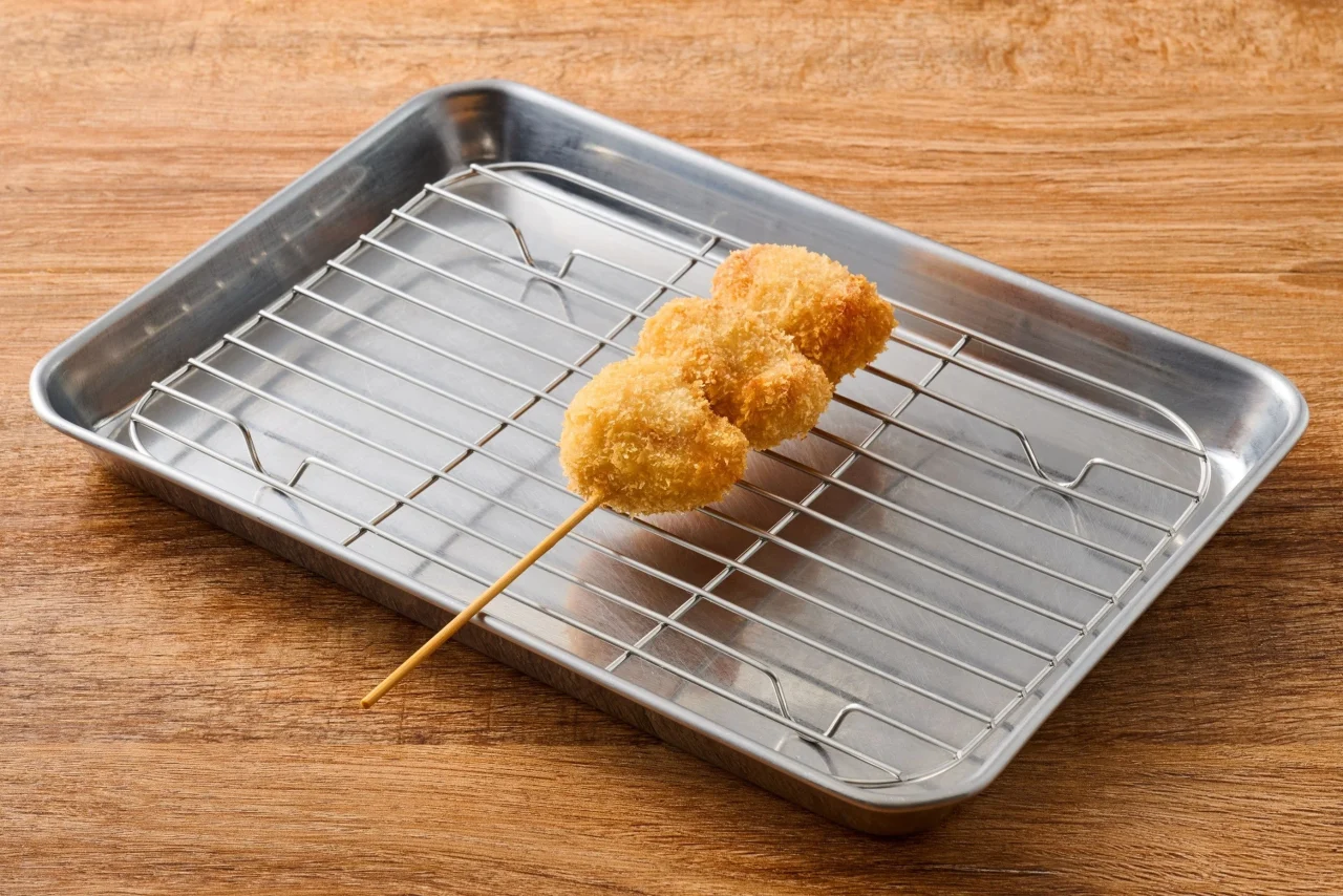 0100たらこ串。3つの揚げた食材が刺さった串カツが金属トレイに置かれている