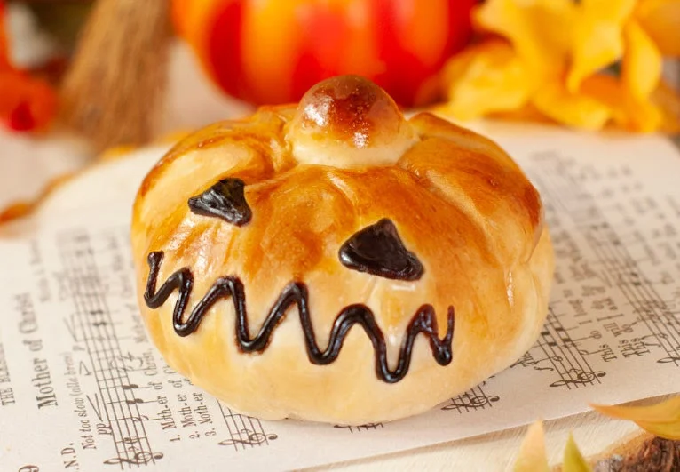 ハロウィンカボチャのパン。ジャック・オ・ランタン風の顔が描かれた丸いパン