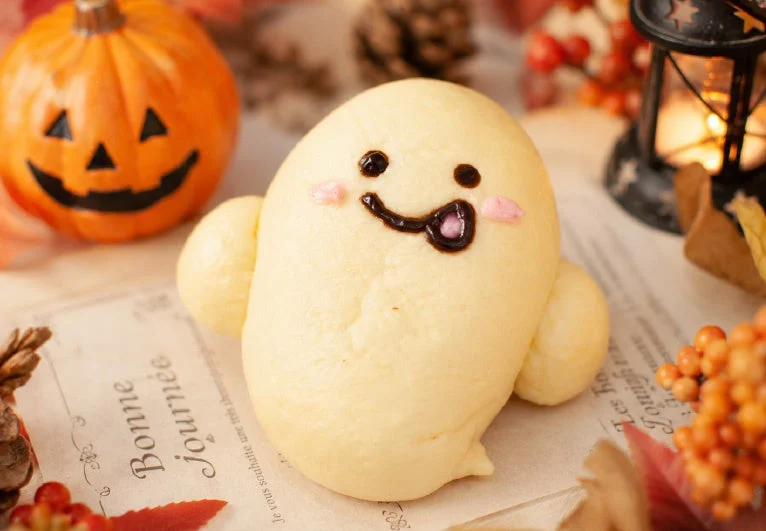ふわふわゴースト。白いパン生地で作られたゴースト型のパンで、チョコで顔が描かれています。