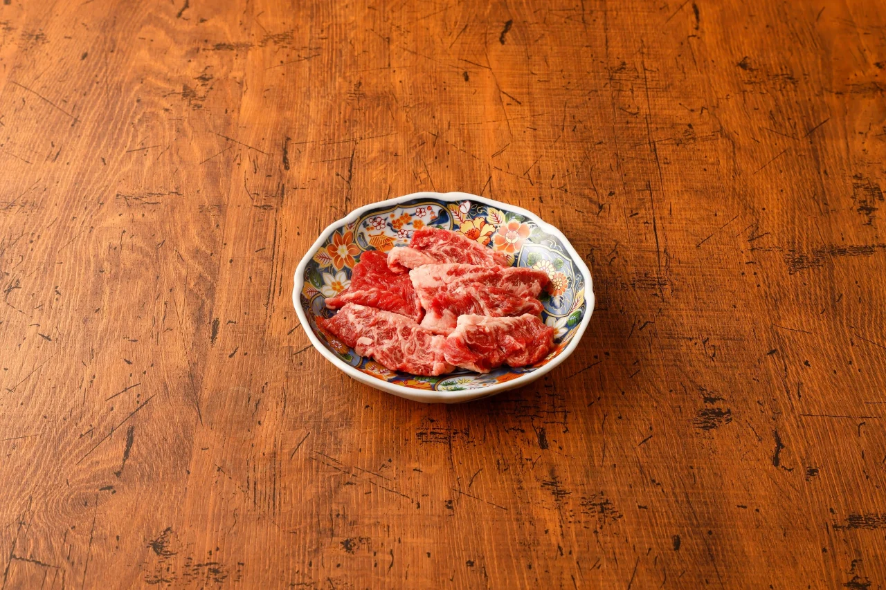 ワタミカルビ中サイズ（通常量）の生肉が花柄の皿に盛り付けられている