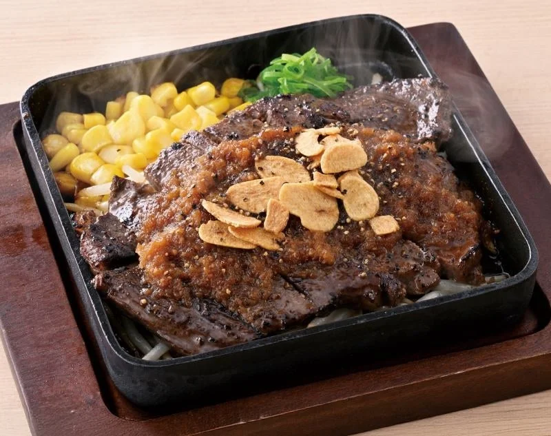 鉄板に盛られた牛肩ロースステーキ、おろしソースと焼きガーリック添え
