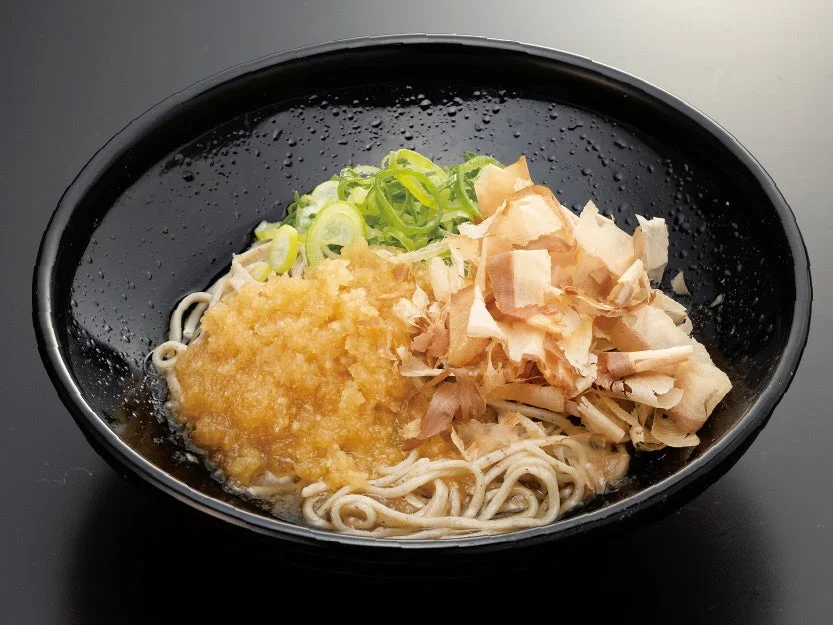 黒い器のおろしそば(冷)。大根おろし、青ねぎ、鰹節をのせた蕎麦