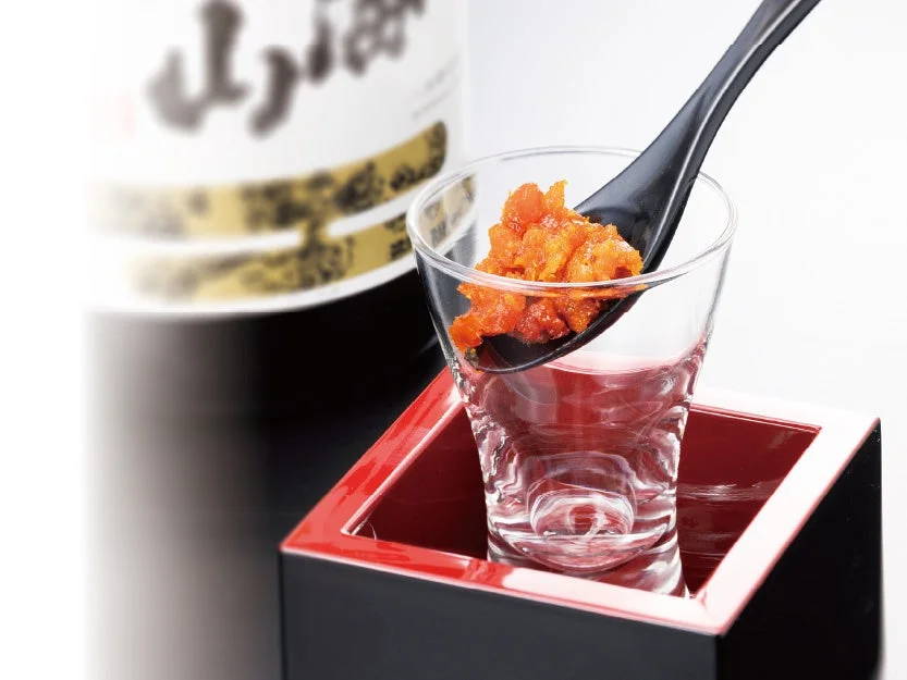 汐うにをれんげに乗せ、日本酒の入ったグラスに添えた盛り付け