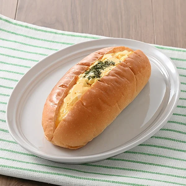 白い皿に盛られた生コッペパン(たまご)で、黄色いフィリングと緑のトッピングが見える