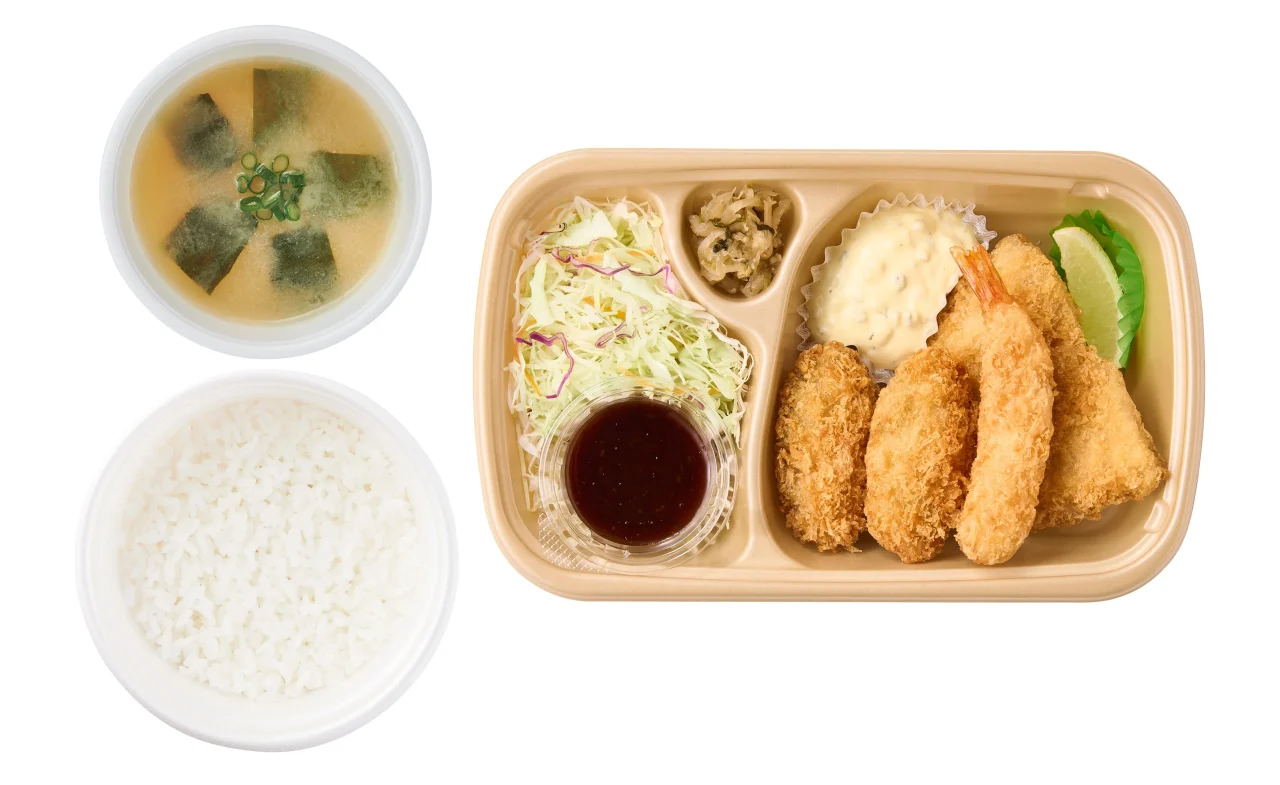 テイクアウト用容器に入ったかきフライミックス定食。ご飯、味噌汁、サラダ、ソース、タルタル、レモン、揚げ物が入っている。