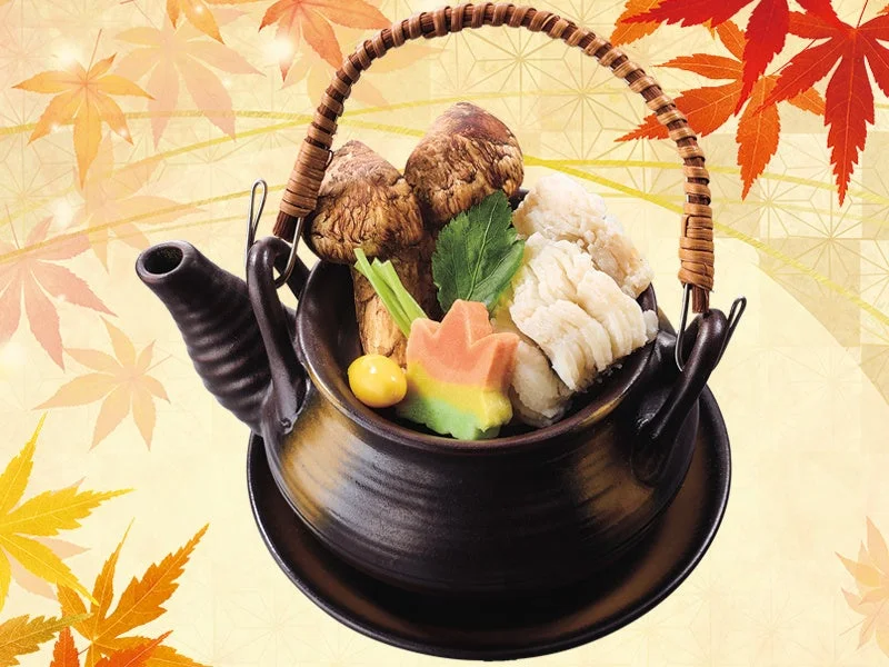 松茸と鱧の土瓶蒸し。黒い土瓶に松茸と鱧が盛り付けられ、秋の紅葉が背景に描かれています。