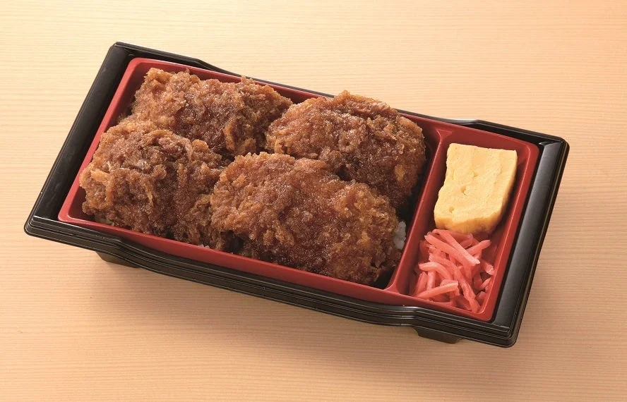 黒い容器に入ったソースカツ重。ご飯の上に揚げたカツが乗っており、卵焼きと紅生姜が添えられている。