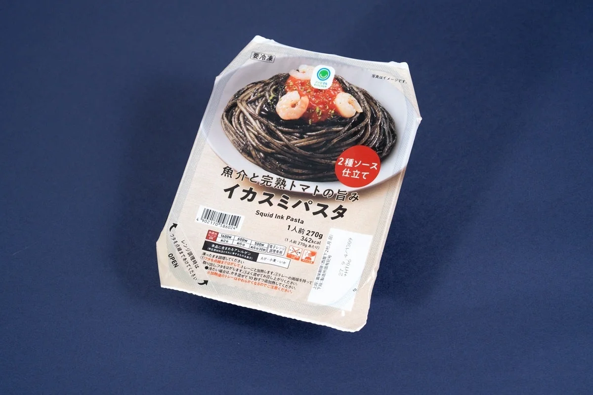 魚介と完熟トマトの旨み イカスミパスタのパッケージと、エビが乗った黒いパスタの盛り付け画像