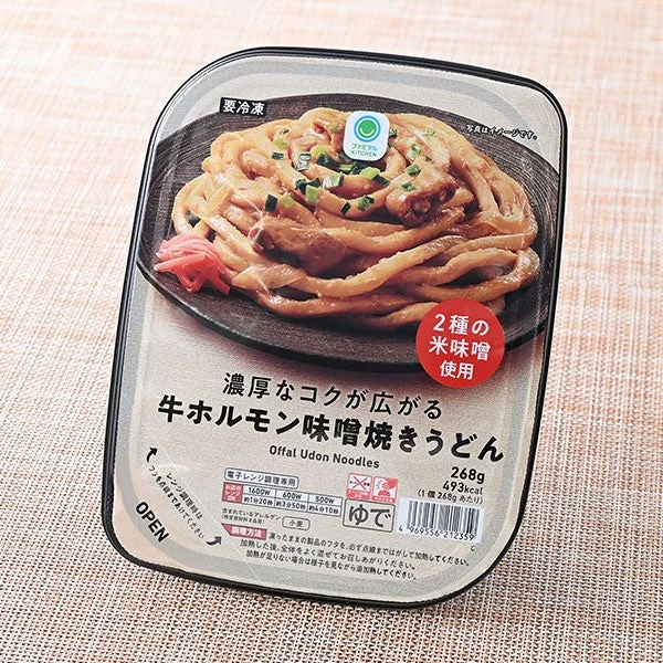 トレー入りの牛ホルモン味噌焼きうどん。黒い器にうどんとネギ、紅生姜が添えられている。