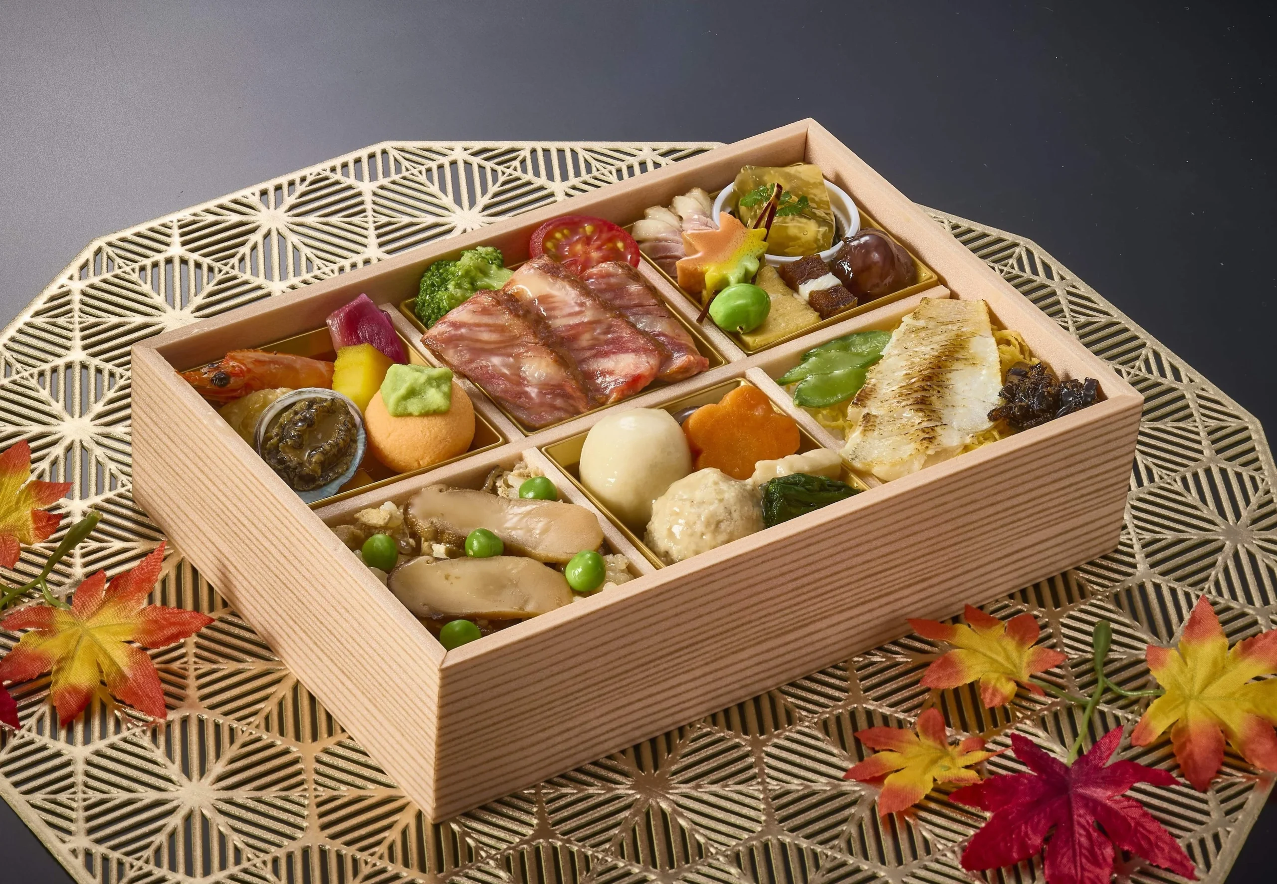 秋の旬彩膳。六つに仕切られた木箱に、魚や野菜など彩り豊かな料理が盛り付けられています。