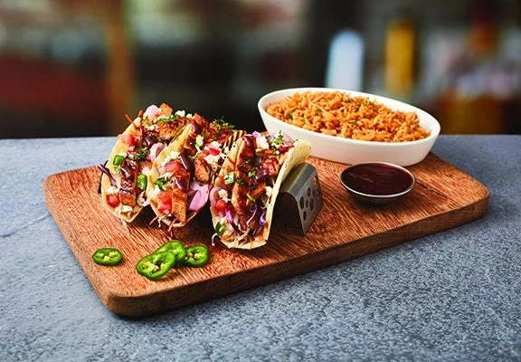 GRILLED CHICKEN FAJITAのタコスとスパニッシュライス、ソースを木製ボードに盛り付けた様子