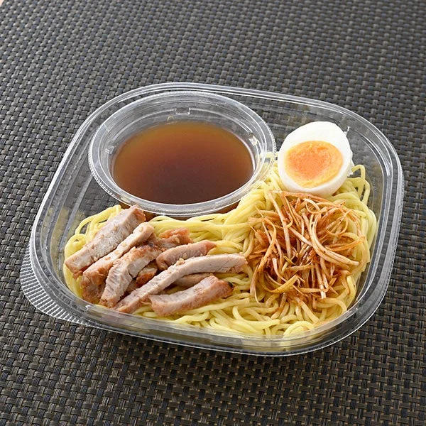 冷しラーメン(黒マー油使用)の容器に入った麺、スープ、チャーシュー、ゆで卵、ねぎ