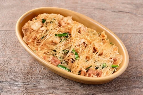 茶色いソースに絡めた揚げ物とネギが盛られた楕円形の皿