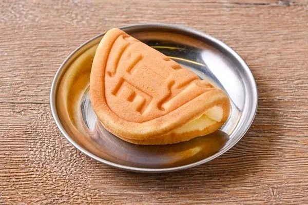 金属の皿に盛られた、表面に文字の型押しがある半円形の焼き菓子