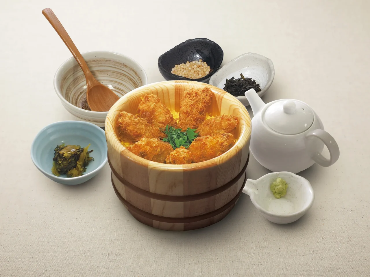 ひとくち牡蠣フライおひつごはん。木製おひつに牡蠣フライとだし茶漬けの具材を添えた写真