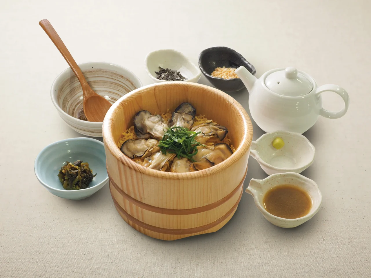 木製のおひつに入ったひとくち浜ゆで牡蠣おひつごはん。だし茶漬けの具材も添えられています。