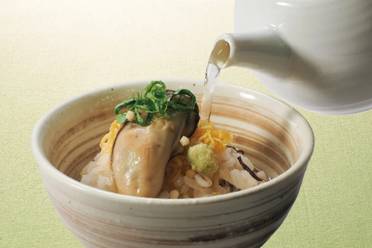 だし茶漬けセット。牡蠣と薬味が乗ったご飯にだしを注ぐ様子。