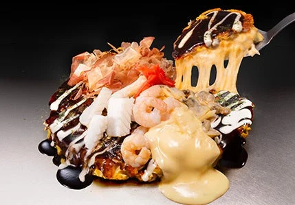 「よくばりチーズ」お好み焼。チーズがとろりと伸び、エビや玉ねぎが乗ったお好み焼き