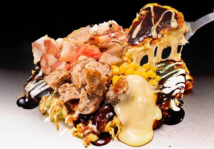 「よくばりチーズ」お好み焼の断面で、チーズがとろけて溢れ出している様子