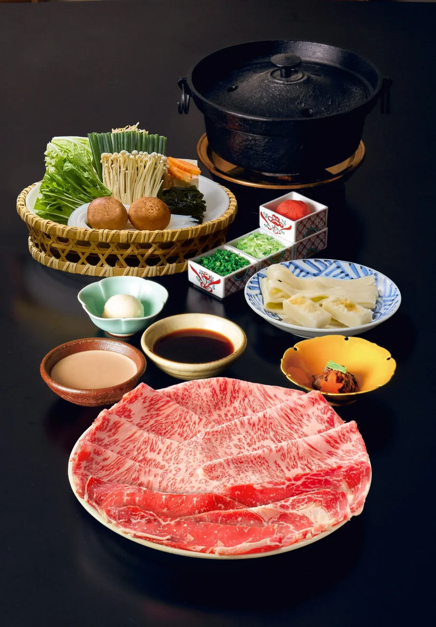 紅白しゃぶしゃぶの提供内容。赤身と霜降りの牛肉、野菜、鍋、薬味などが並ぶ。
