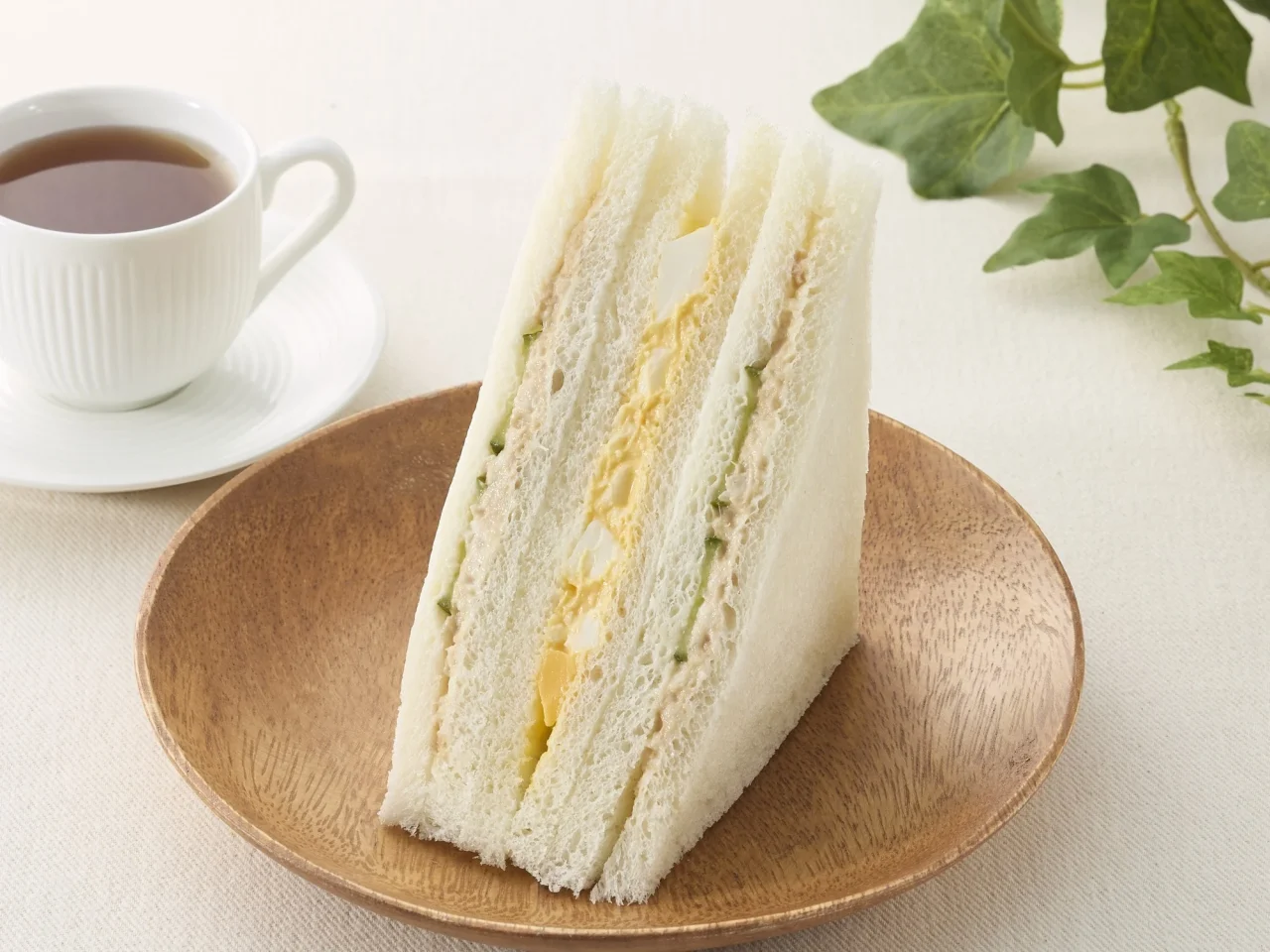 ツナたまごサンドの通常サイズイメージ画像。木皿に盛られたサンドイッチとコーヒーが写っている。