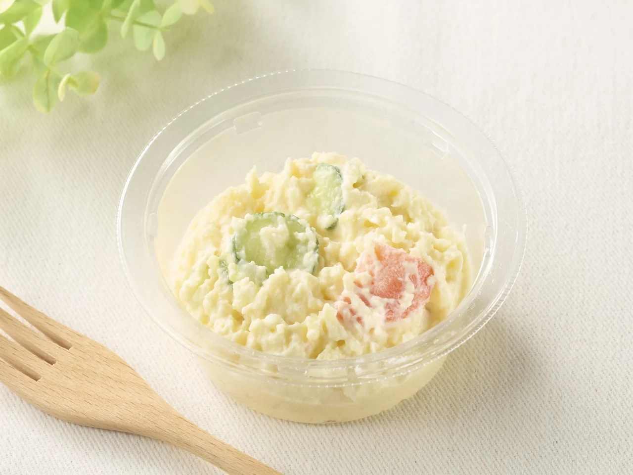 なめらかポテトサラダの通常サイズ。透明容器に入ったポテトサラダと木製フォーク