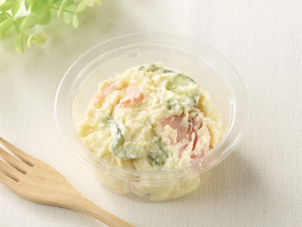 なめらかポテトサラダ増量イメージ画像。透明容器に入ったポテトサラダと木製フォーク